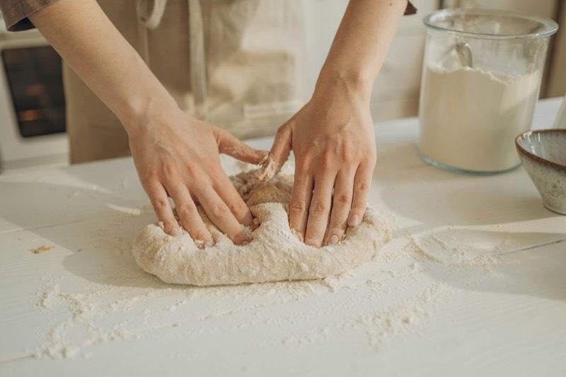 Hands kneading sourdough bread dough on a floured surface