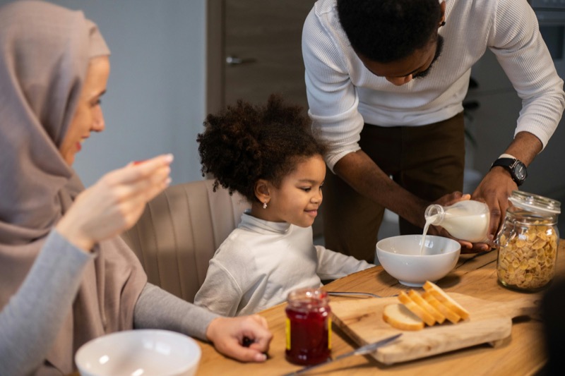 Family enjoying breakfast with bread, milk, and jam